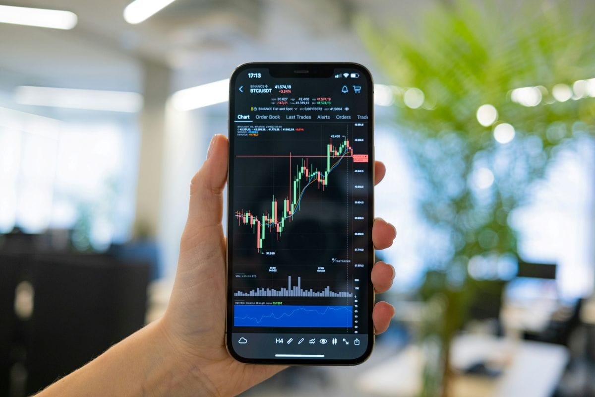 Person holding smartphone showing stock trading chart — illustration of overtrading risk for investors